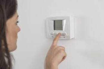 woman trying to change thermostat
